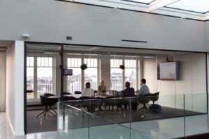 A Board of four people meet in a glass board room around a dark table. Making Better Board Meetings improves the experience for everyone! CDS Fundraising. 