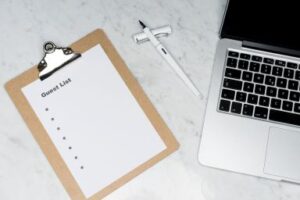 A Clipboard marked invites next to a laptop on a granite table. CDS Fundraising 