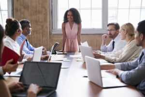 Black businesswoman addressing colleagues at a board meeting. Learn how to build a more effective board.