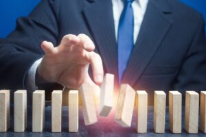 A man ruins the order of a standing domino row, showing the dangers of taking anecdotal learning as fact.