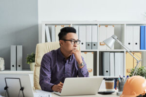 Pensive Asian man thinking about continuous improvement. Custom Development Solutions