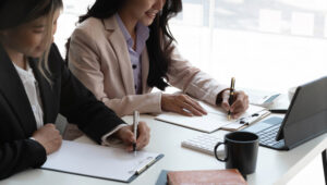 Two young Asian businesswomen work together to analyze work at the office.