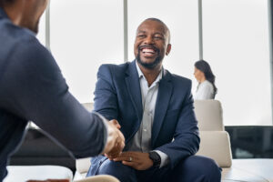 Two smiling businessmen shaking hands in a modern office.