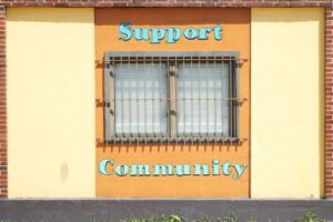 For CDS Fundraising Blog An image of a window and wall with Blue words "Support Community" on the top and bottom of the window.