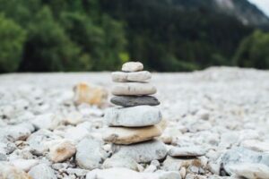 A stack of rocks balancing on a rocky beach. Balancing nonprofit resources can be like making a tower of rocks. CDS Fundraising 