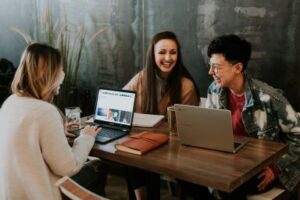 Three young people sit around a table laughing. You must connect with people to truly succeed. CDS Fundraising. 