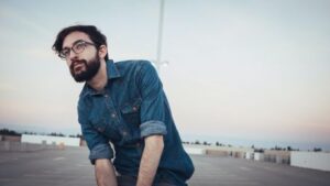 A smiling man with glasses and a dark beard in an empty parking lot. CDS Fundraising Inc.