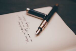 A letter on a dark desk with a nice fountain pen on top. Proposals to Foundations can begin with letters. Custom Development Solutions.