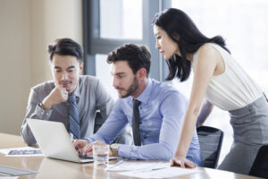 Three business people discussing prospect evaluation in a meeting room