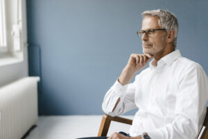 Man sitting in office chair, thinking about finding major gift prospects.