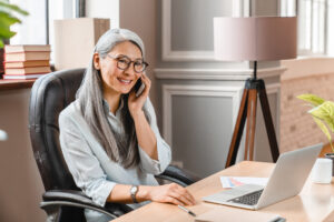 Mature businesswoman discussing fundraising success on the phone at Custom Development Solutions.