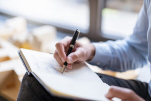 Close-up of a businessman taking notes for a campaign feasibility and planning study for Custom Development Solutions