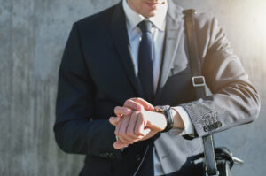 Businessman in suit looking at his watch, thinking about how to seize the day in a capital campaign. Custom Development Solutions