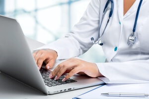 A doctor types on a laptop